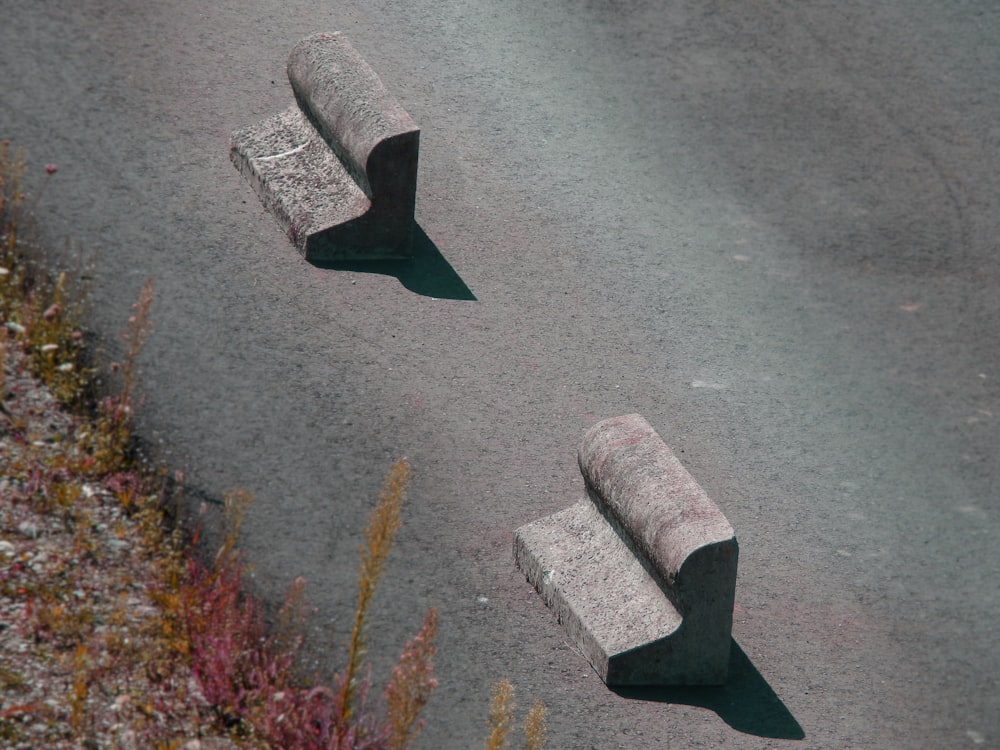 a couple of cement benches sitting on the side of a road