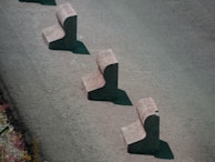 Three concrete barriers are aligned in a staggered pattern on a paved surface. Each barrier has a chunky, L-shaped design, casting shadows on the ground.