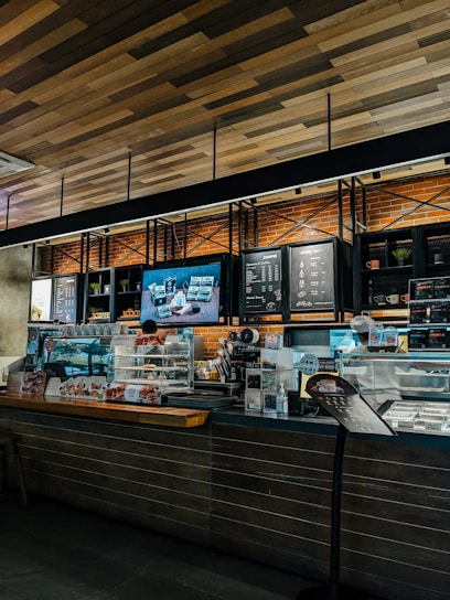 Cozy coffee shop interior with fresh pastries displayed on wooden shelves.