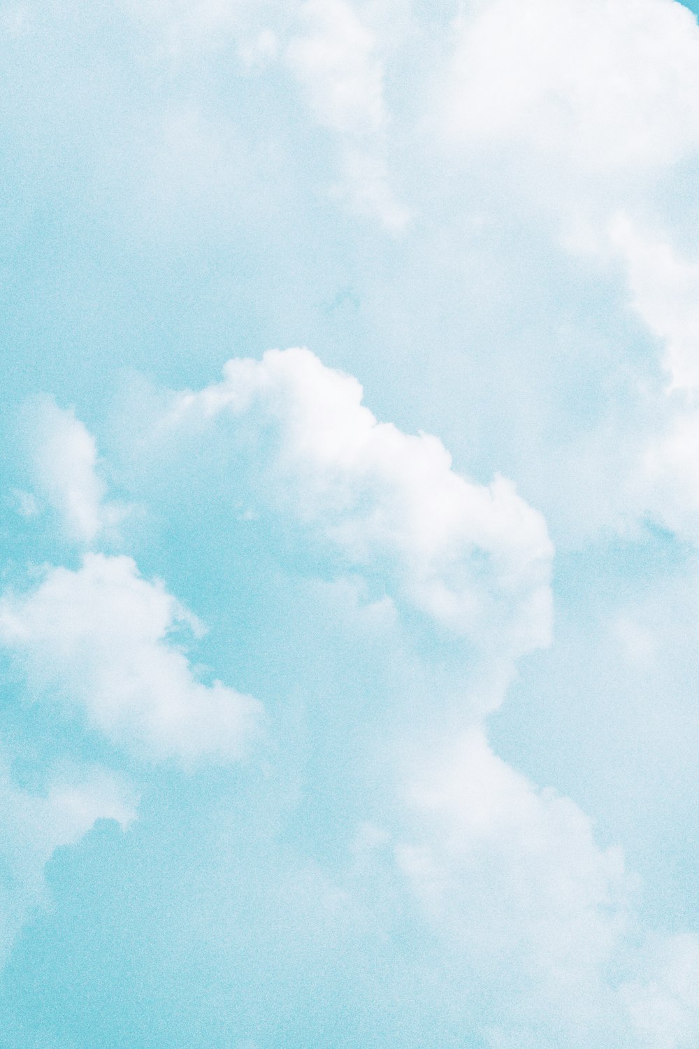 a plane flying through a cloudy blue sky