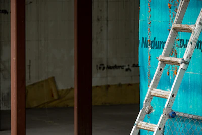 An industrial aluminium ladder positioned against a warehouse wall.
