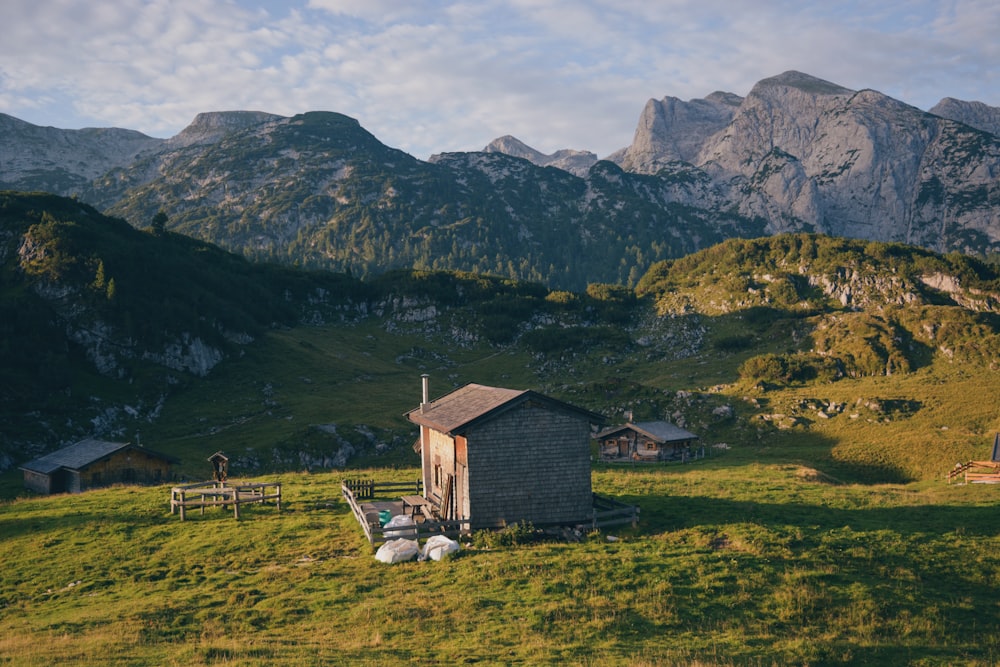 a small cabin in a field with mountains in the background