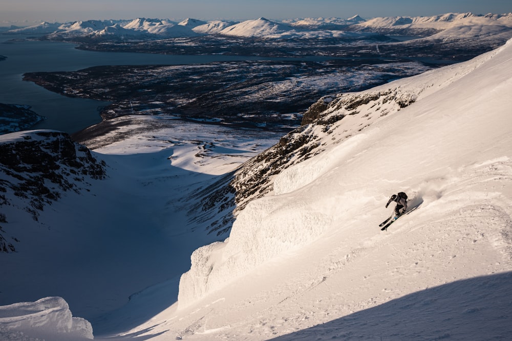 a person skiing down a snowy mountain with mountains in the background