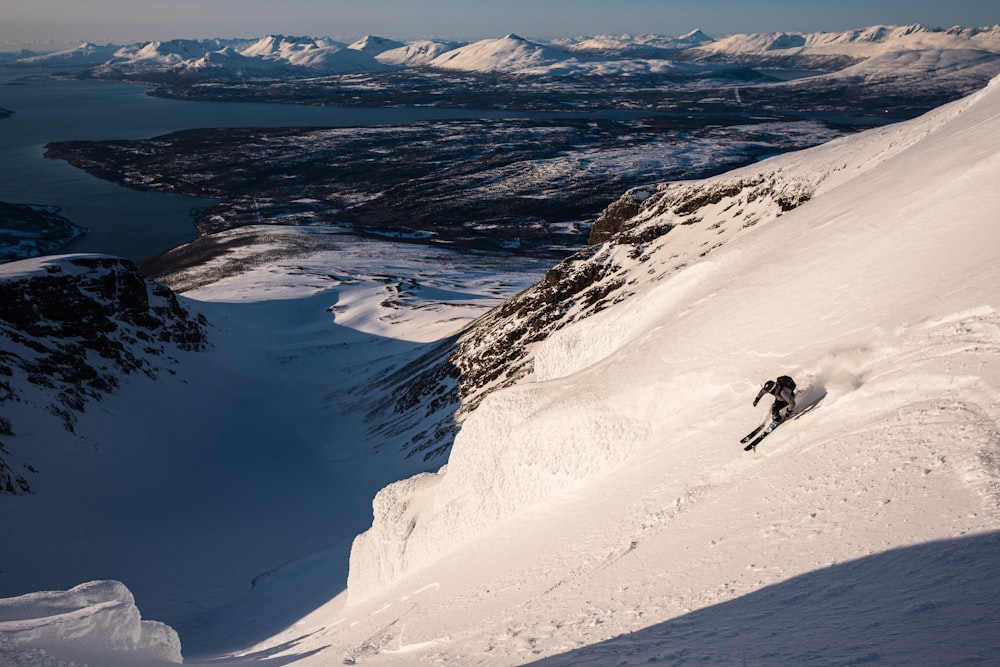 산을 배경으로 눈 덮인 산에서 스키를 타는 사람