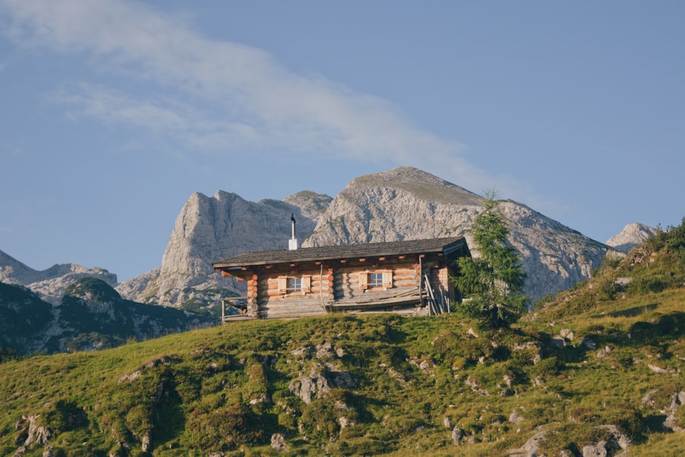 a cabin on a hill with mountains in the background