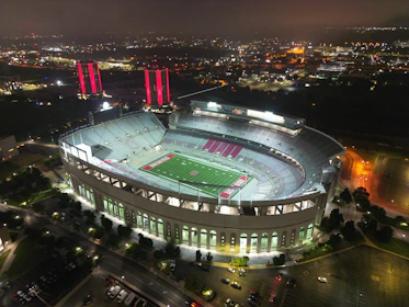 A panoramic view of a packed football stadium at dusk, with vibrant neon accents glowing subtly.