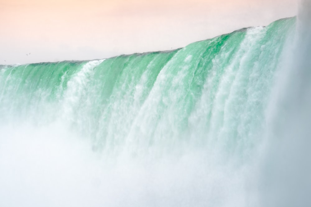 a man riding a surfboard on top of a large waterfall