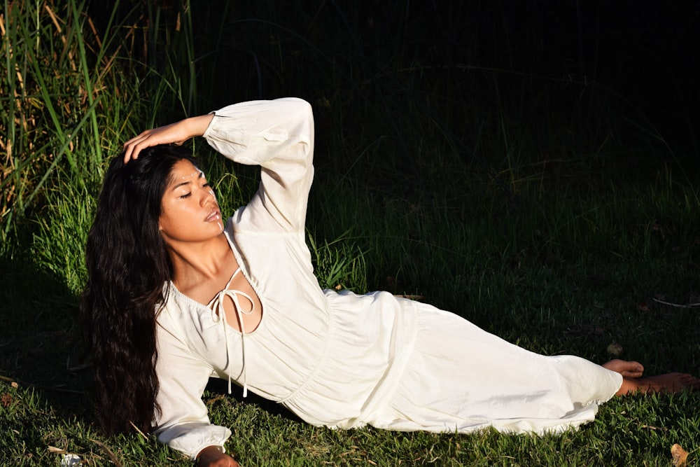 a woman laying on the ground in a white dress