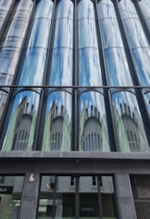 A sleek London office building showcasing large, reflective glass panels with steel framing.