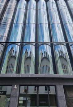 A sleek London office building showcasing large, reflective glass panels with steel framing.