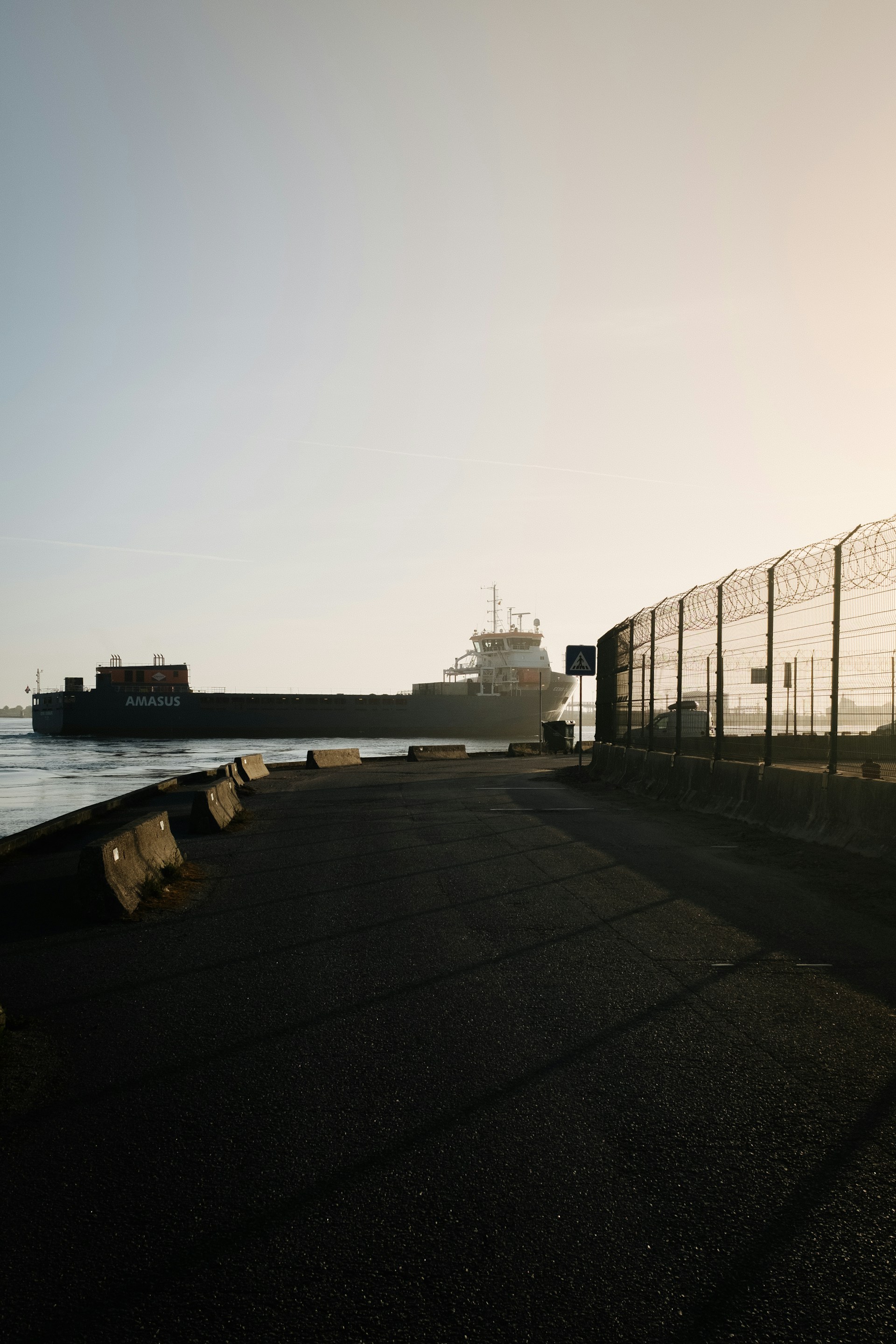 a large cargo ship in the water behind a fence