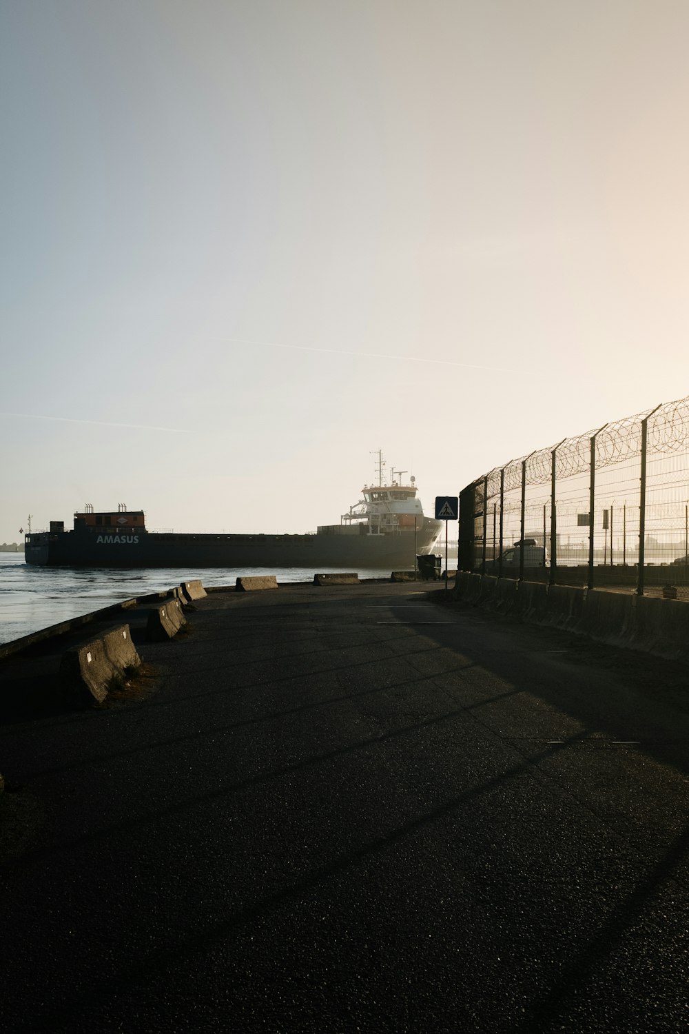 a large cargo ship in the water behind a fence