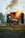 A firefighter in protective gear is actively extinguishing a fire using a hose, with flames and smoke emanating from a burning structure.