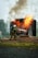 A firefighter in protective gear is actively extinguishing a fire using a hose, with flames and smoke emanating from a burning structure.