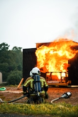 a fireman in front of a fire with a hose