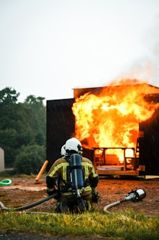 a fireman in front of a fire with a hose