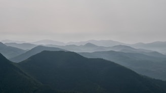 A tranquil scene of mountain tops fading into the distance under a soft sky.