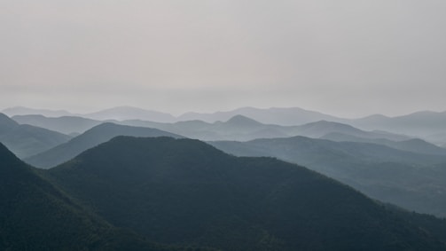 A tranquil scene of mountain tops fading into the distance under a soft sky.