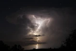 Dynamic action shot of Naruto and Sasuke facing off under a stormy sky