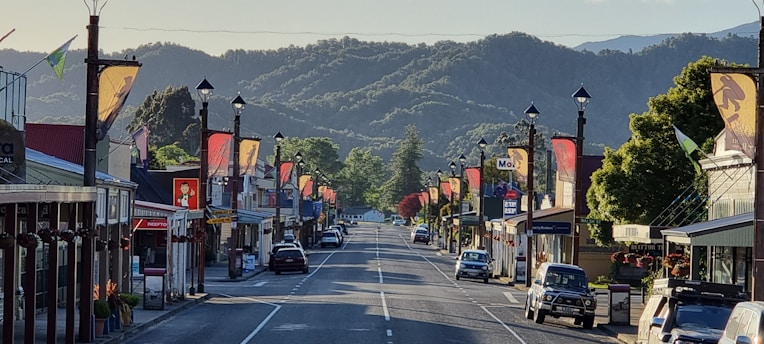 A cozy small-town street with local shops and colorful banners promoting discounts.