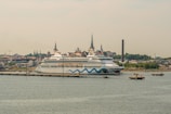 A panoramic view of a cruise ship docked near a historic European port.