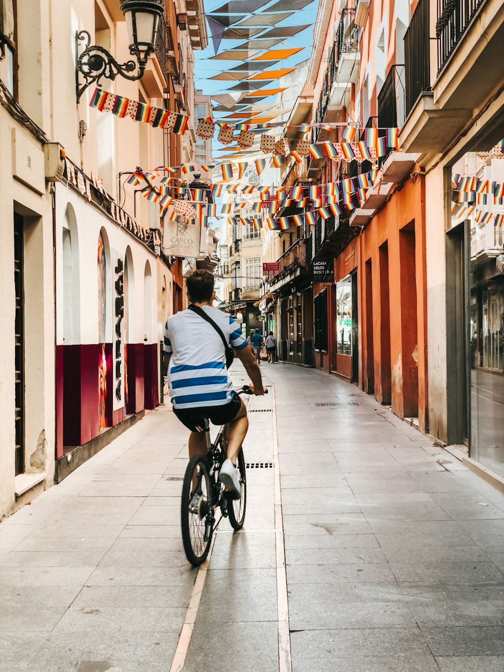 a man riding a bike down a street next to tall buildings