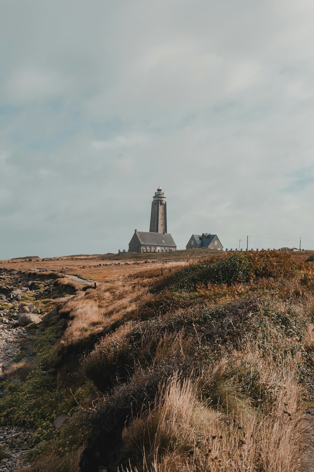 a lighthouse on top of a grassy hill