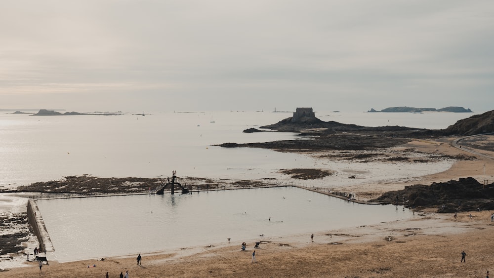 a group of people standing on a beach next to a body of water