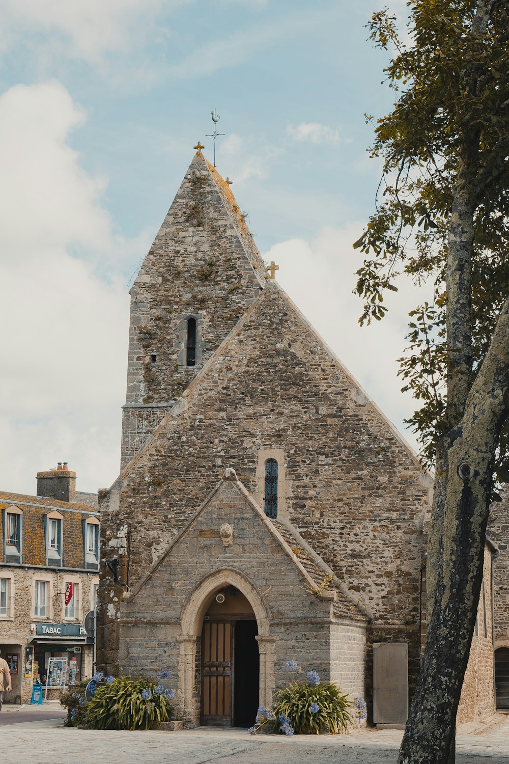 uma igreja de pedra com uma árvore à sua frente