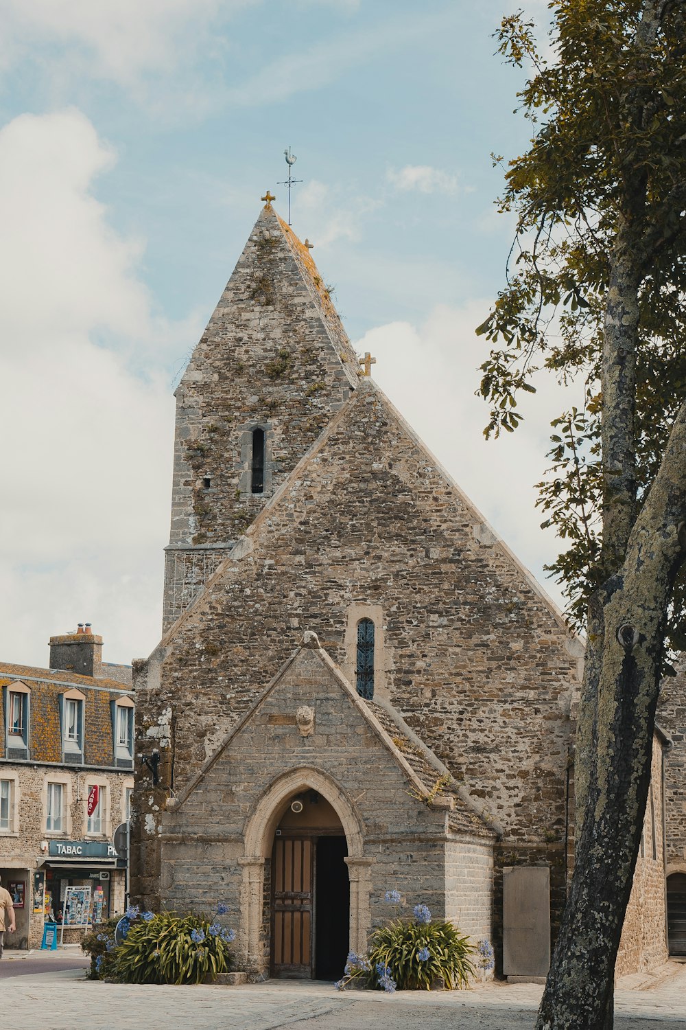 a stone church with a tree in front of it