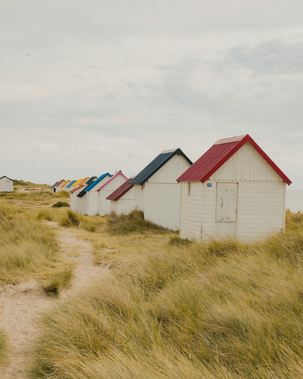 une rangée de cabanes de plage assises au sommet d’une plage de sable