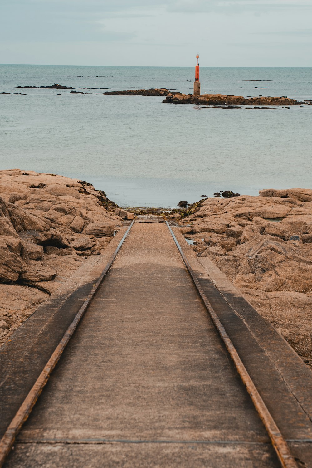 eine Bahnstrecke, die zu einem Leuchtturm im Ozean führt