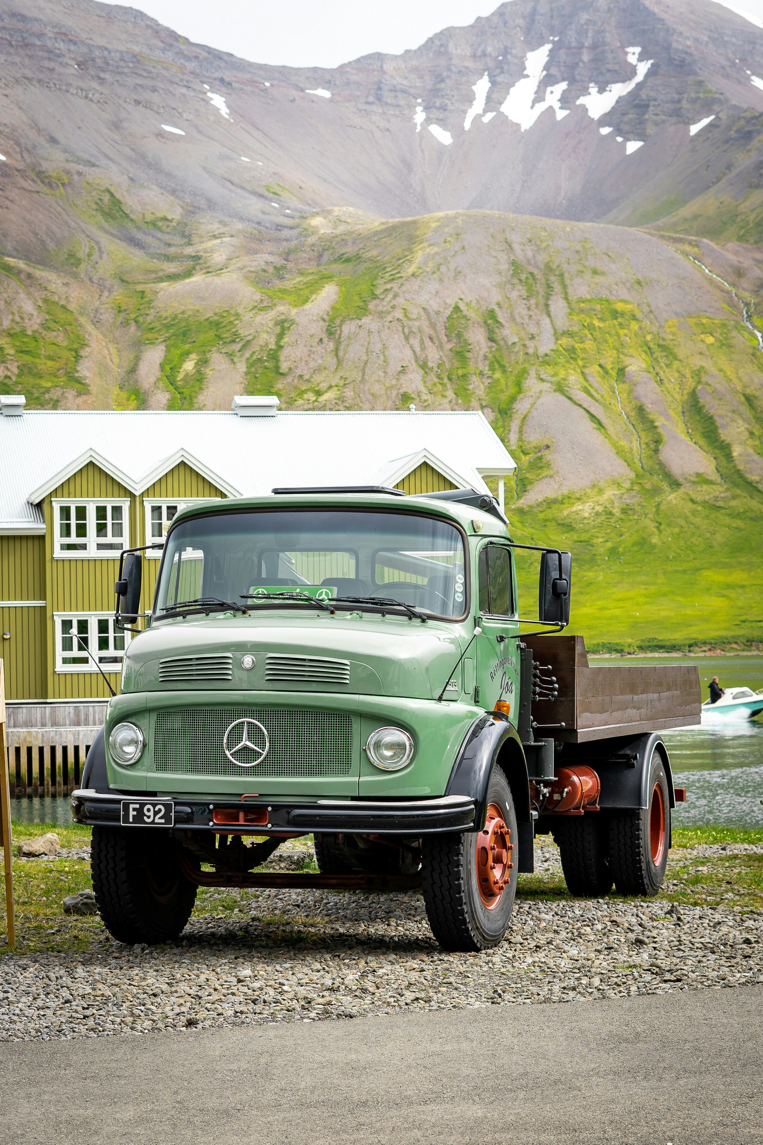 a green truck parked in front of a mountain