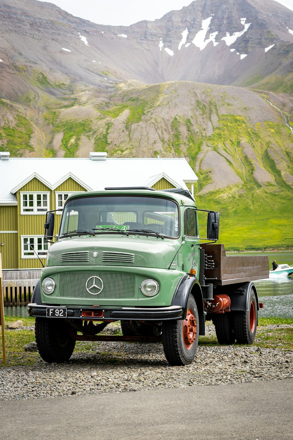 a green truck parked in front of a mountain