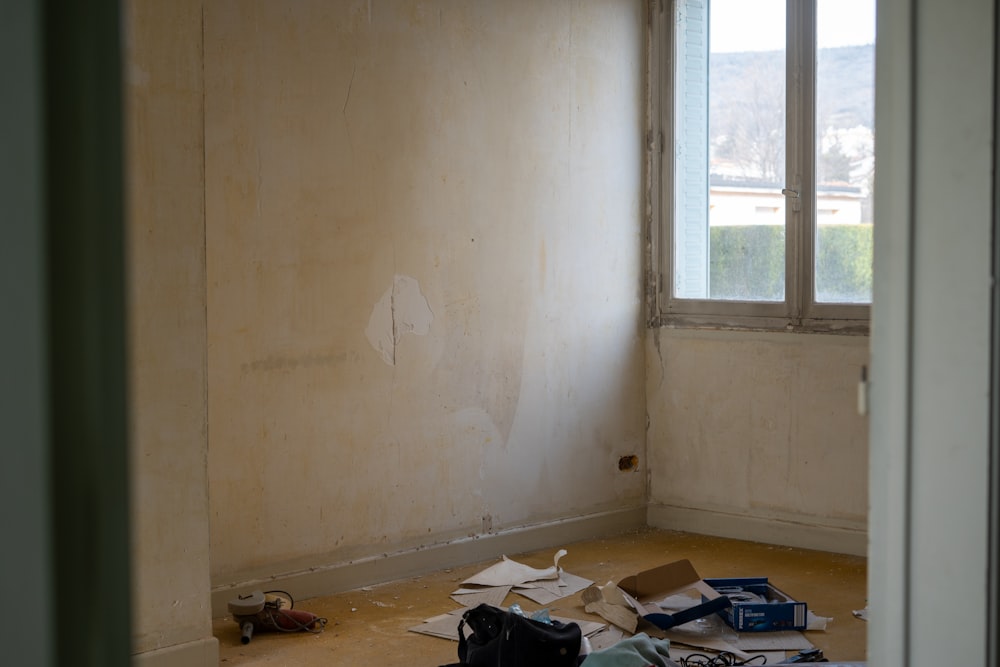 Ein Zimmer mit einem Fenster und einem Haufen Gegenstände auf dem Boden