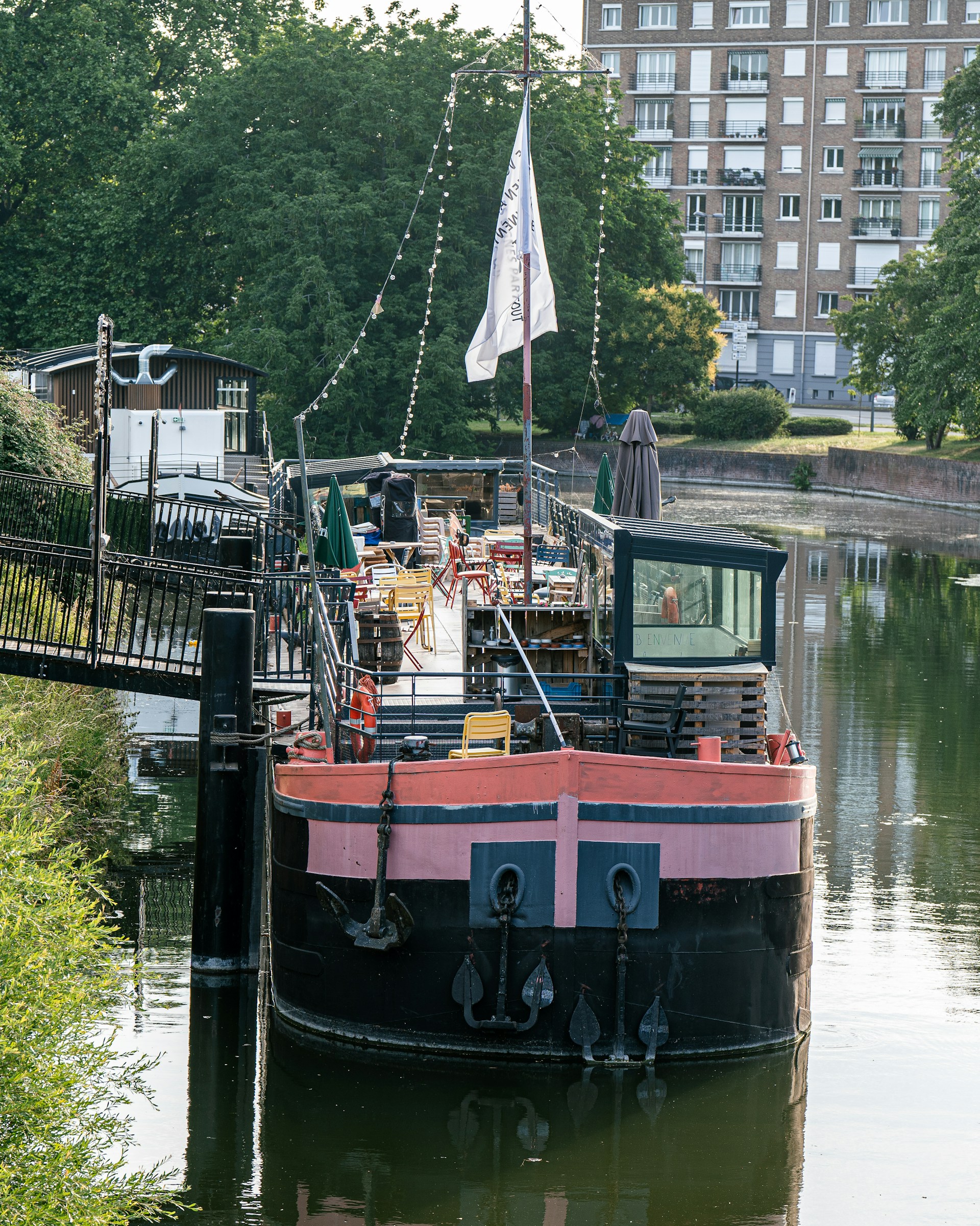 The sunny outdoor seating area of The Boat Inn overlooking the peaceful Grand Union Canal, with guests enjoying their meals.