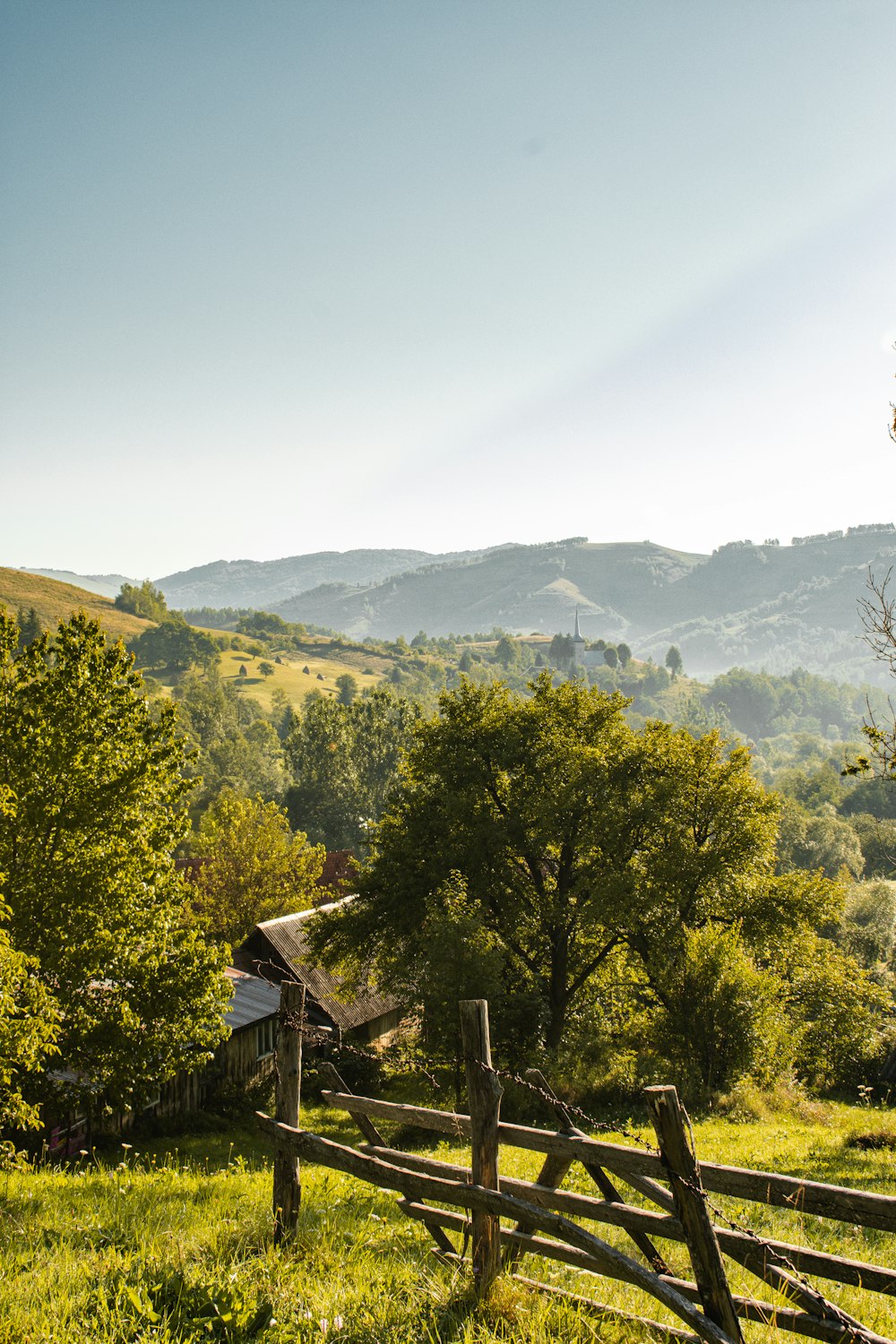 a wooden fence in a field with mountains in the background