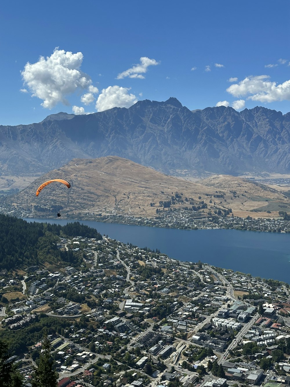 a paraglider flying over a city with mountains in the background