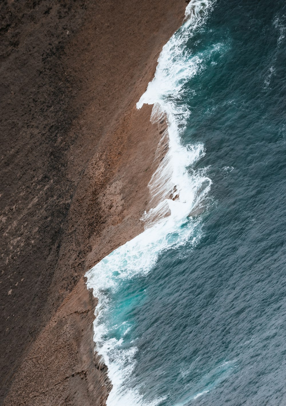 una persona che cavalca una tavola da surf su una spiaggia coperta di onde