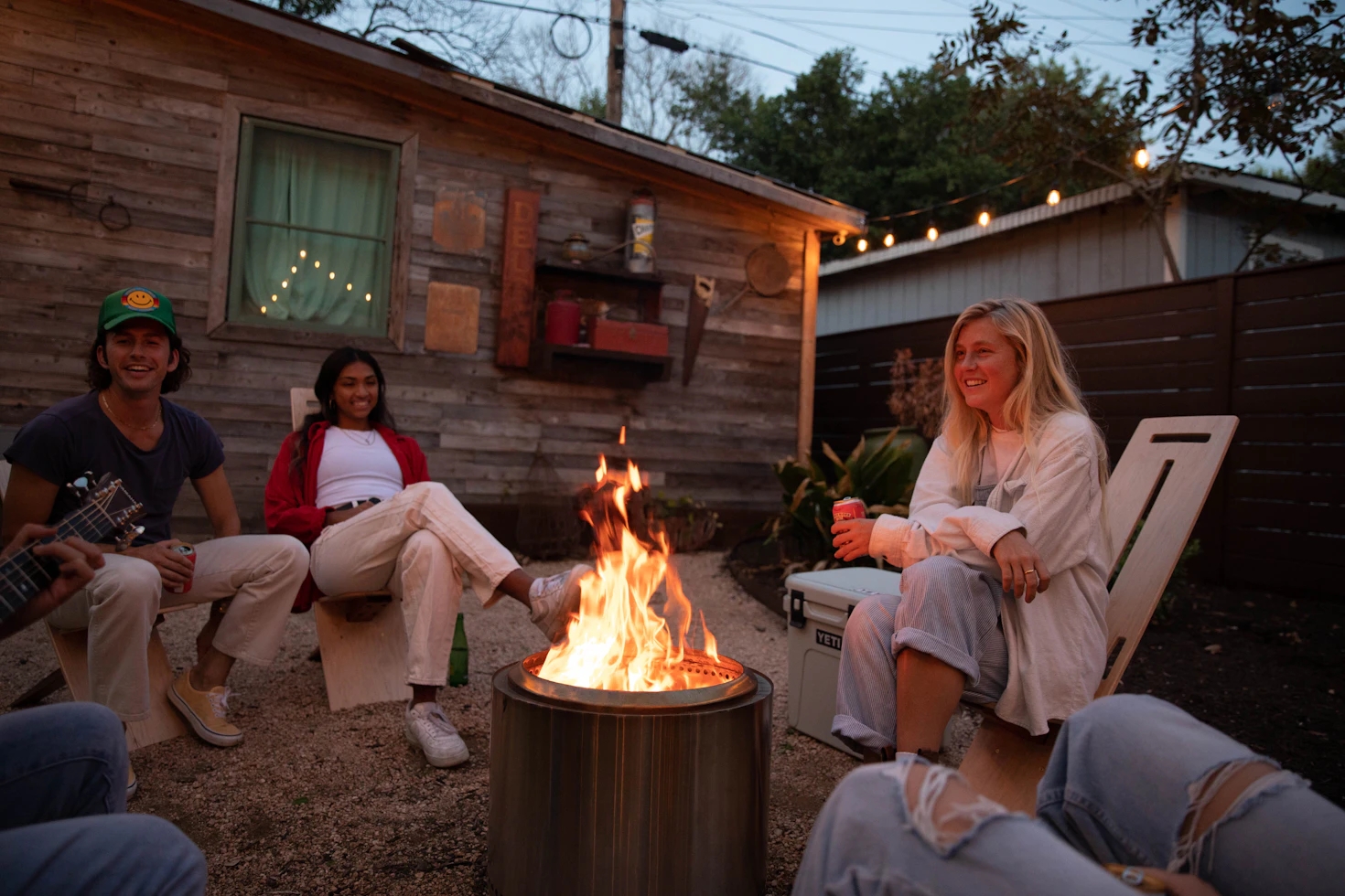 Friends gathering around a modern backyard fire pit at night