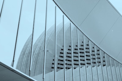 An architectural structure with a curved, modern design. The image features a large building with a series of vertical lines and geometric shapes. The glass and metal elements reflect a sleek and futuristic style.