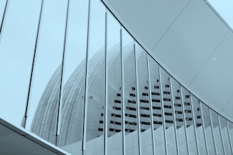 An architectural structure with a curved, modern design. The image features a large building with a series of vertical lines and geometric shapes. The glass and metal elements reflect a sleek and futuristic style.