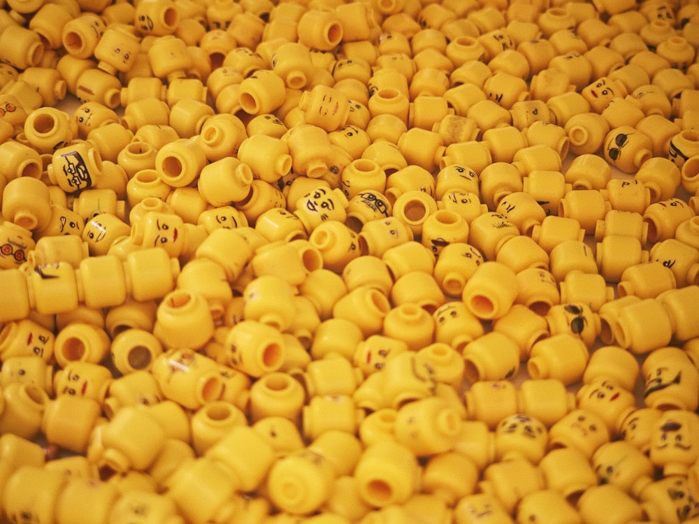 a pile of yellow ceramic beads with faces on them