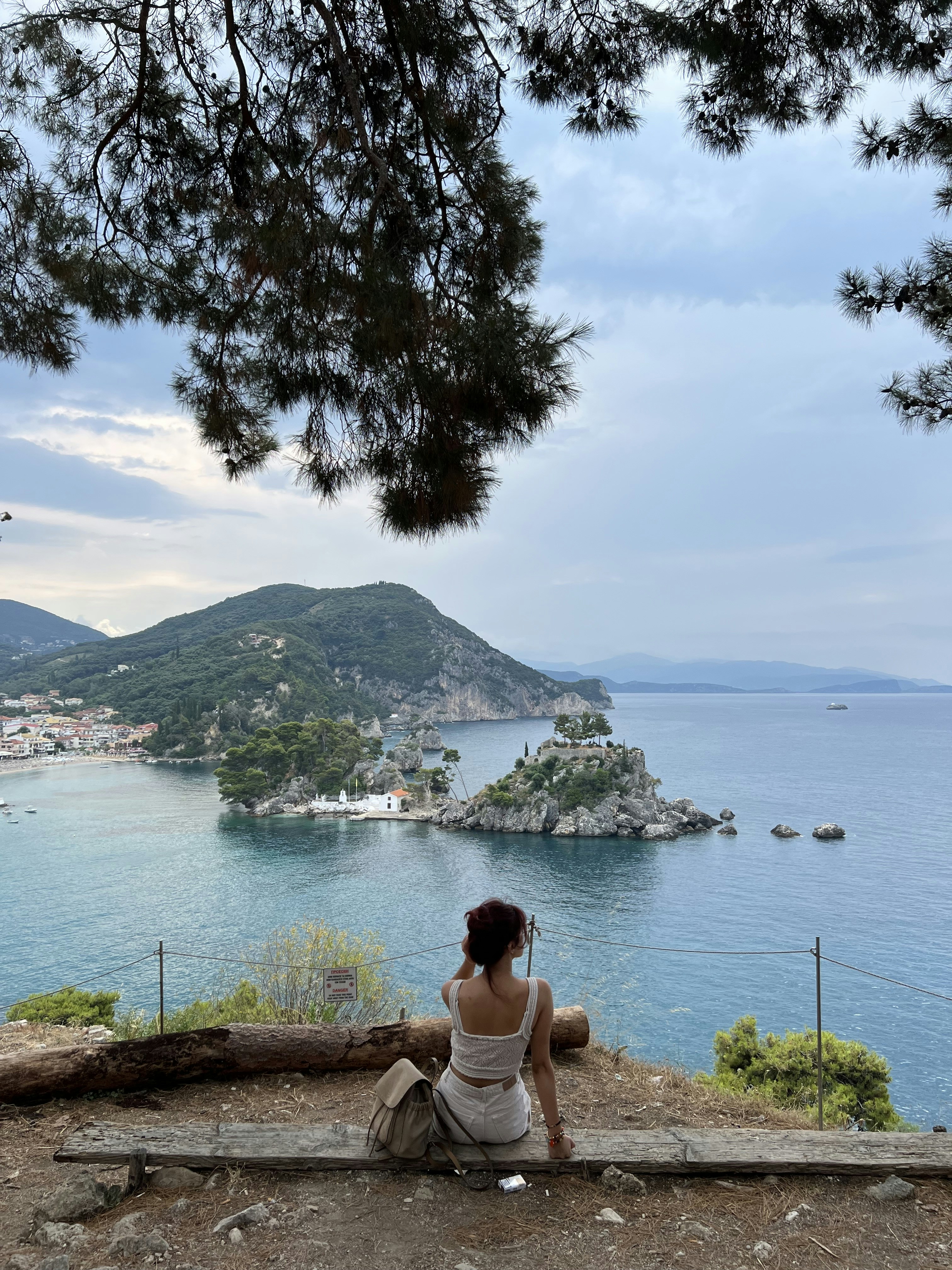 a woman sitting on a bench looking at the water