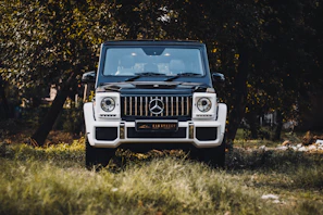 An influencer shaking hands with a brand representative beside a luxury SUV.