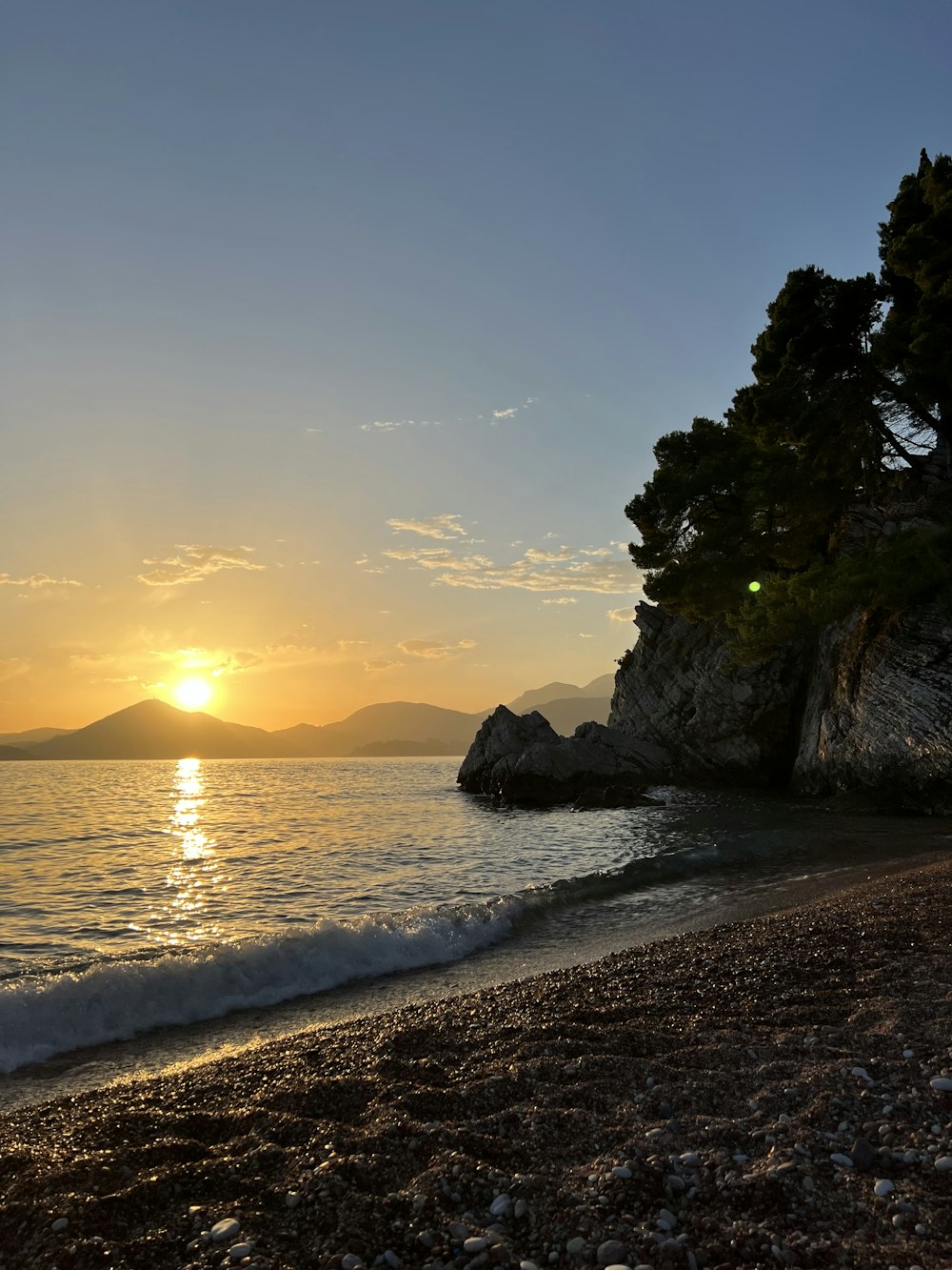 the sun is setting over the water at the beach