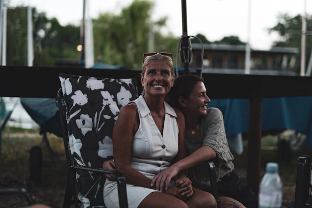 Two people sitting on wooden chairs in nature, sharing their feelings warmly.