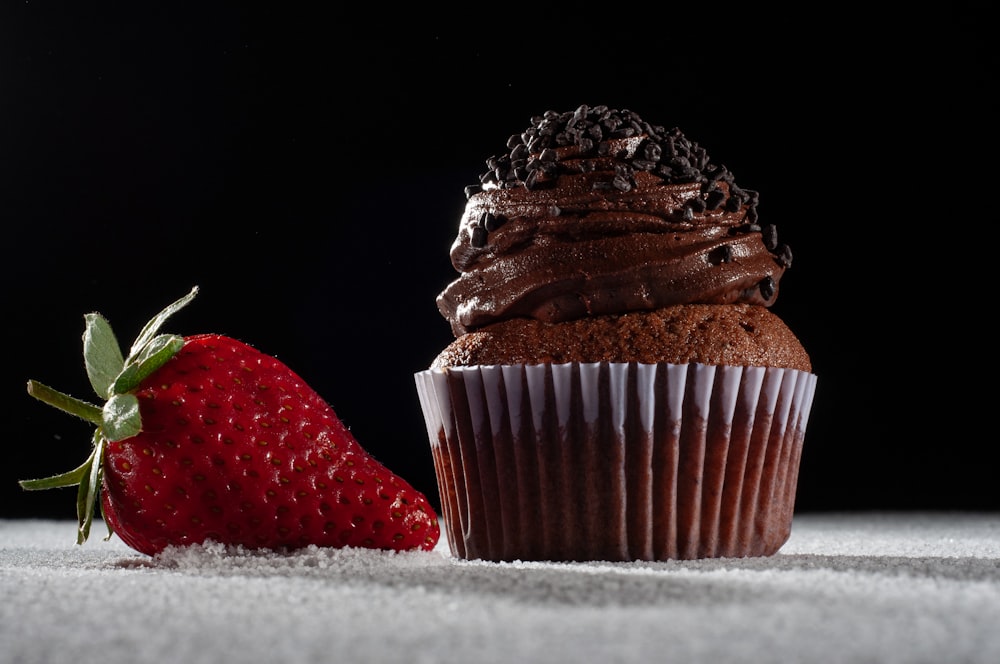 a chocolate cupcake and a strawberry on a table