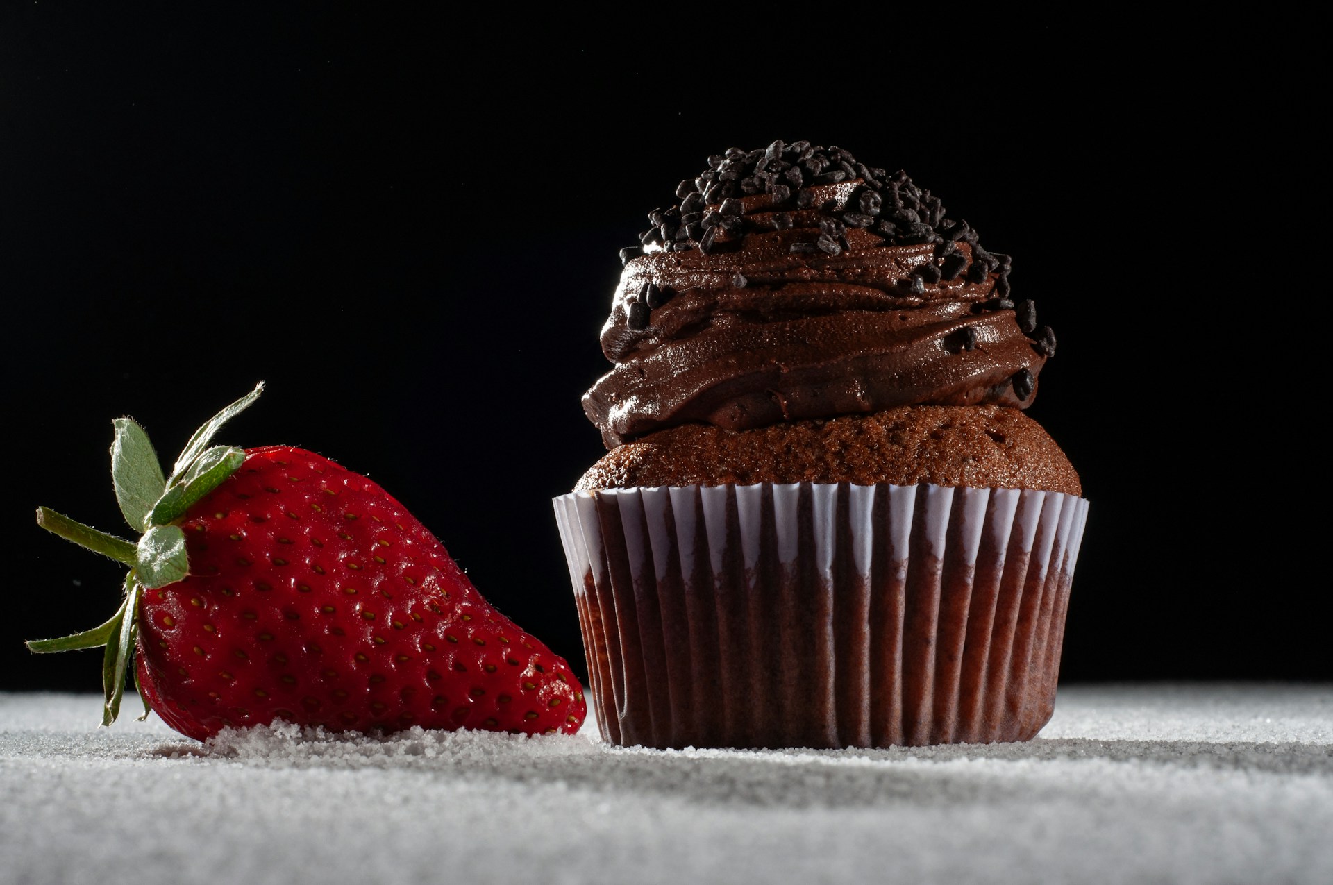 a chocolate cupcake and a strawberry on a table