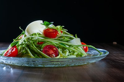 a glass bowl filled with a salad on top of a wooden table